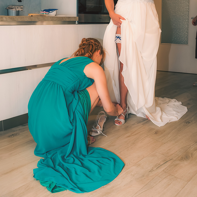Immagine di damigella che sistema la scarpa alla sposa, foto di Ferruccio Munzittu