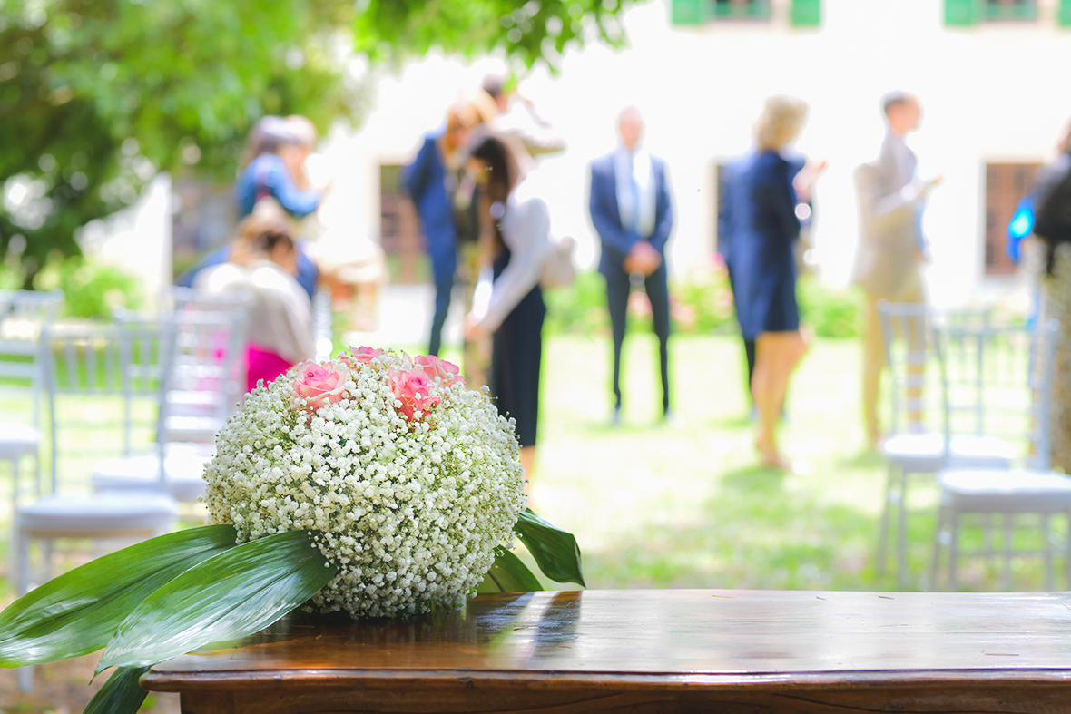 Immagine di una composizione floreale e, nello sfondo, gli ospiti del matrimonio, foto di Ferruccio Munzittu